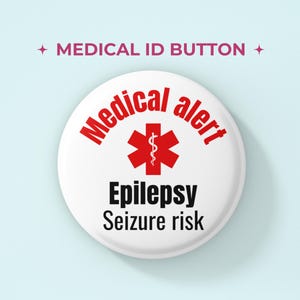 Puede incluir: Un botón redondo blanco con el texto MEDICAL ID BUTTON en la parte superior. El centro muestra un símbolo rojo Star of Life con las palabras Medical alert en rojo, seguidas de Epilepsy y Seizure risk en negro.