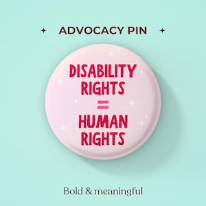以下が含まれることがあります： ライトピンクの背景にダークピンクの文字で「DISABILITY RIGHTS = HUMAN RIGHTS」と書かれた丸いピンバッジ。デザインには小さな白い星のアクセントが含まれています。ピンの上部には「ADVOCACY PIN」、下部には「Bold & meaningful」と記載されています。
