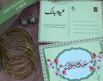 May include: An assortment of gold bangles and earrings are displayed with two greeting cards. The cards feature floral designs and text in a foreign language. The words "EID VINTAGE STYLE CARDS" are printed on a green diagonal banner.