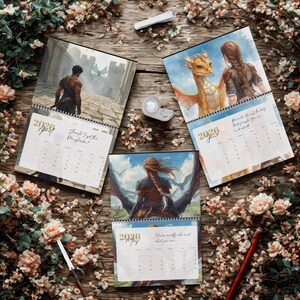 May include: Three 2026 wall calendars featuring fantasy illustrations of characters and dragons. The pages display months including April, May, and June with printed text. The calendars are spiral-bound and arranged on a wooden surface with floral accents.