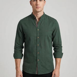 Peut inclure: Une chemise vert foncé à manches longues avec un col officier et une fermeture boutonnée. La chemise présente un petit détail brodé sur la poitrine et des poignets boutonnés. Le col a un détail rayé rouge et blanc. La chemise est en tissu texturé.