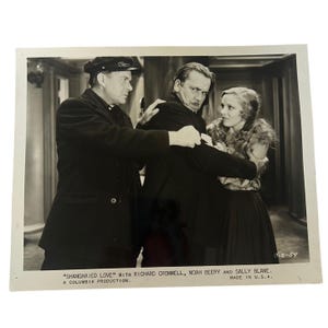 May include: A black and white vintage film still featuring three individuals in a dramatic scene. Text at the bottom reads: SHANGHAIED LOVE WITH RICHARD CROMWELL, NOAH BEERY AND SALLY BLANE. A COLUMBIA PRODUCTION. MADE IN U.S.A. C-2-59.