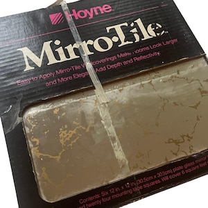 May include: A Hoyne Mirro-Tile box containing six 12 in. x 12 in. plate glass mirror squares with a gold marbled pattern. The black packaging features the text 'Mirro-Tile' and 'Easy to Apply Mirro-Tile Wallcoverings Make Rooms Look Larger'.