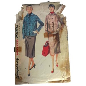 以下が含まれることがあります： 2つの服装のイラストが描かれたヴィンテージのSimplicity型紙封筒。1つは青いジャケットとダークスカート、もう1つはチェック柄のコートとスカート、赤いバッグの組み合わせです。紙製の封筒は使い古されており、端が破れています。