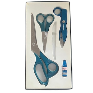 May include: A Singer sewing kit set in a rectangular box containing a large pair of teal-handled scissors, a smaller pair of teal-handled scissors, a teal seam ripper with the brand name SINGER printed on it, and a small blue needle threader.
