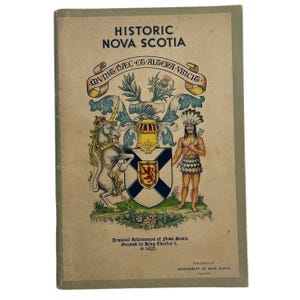 May include: A softcover book titled Historic Nova Scotia with a light tan cover. The front features the colourful Armorial Achievement of Nova Scotia, including a unicorn, a person in traditional attire, a shield, and the Latin text Munit Haec et Altera Vincit.