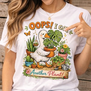 Peut inclure: T-shirt blanc avec une illustration d'un canard tenant une plante en pot, entouré d'autres plantes en pot et le texte "OOPS! I GOT Another Plant!". Le motif comprend des papillons et des fleurs.