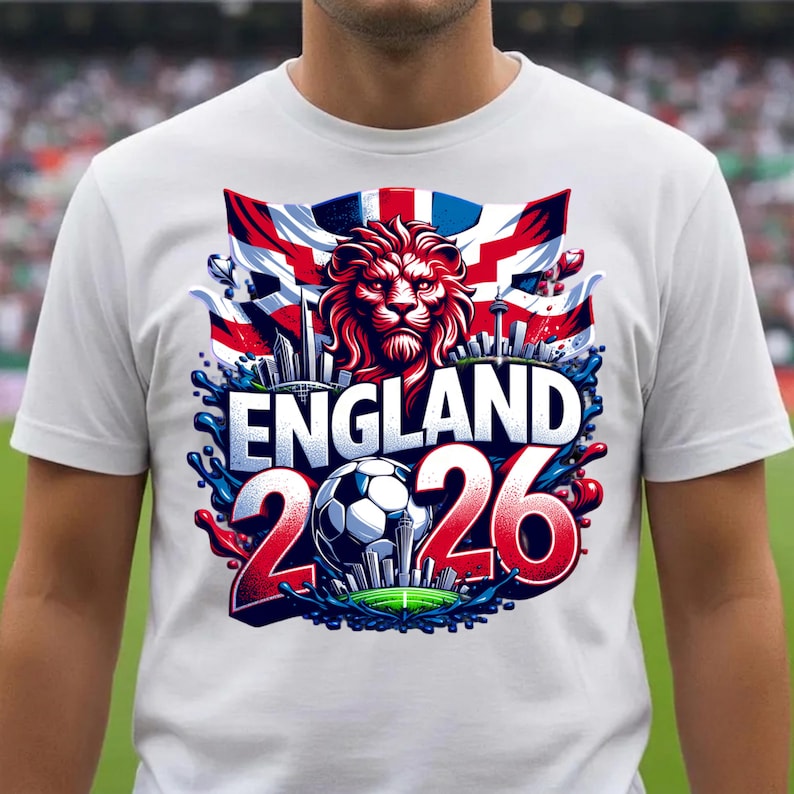K&ouml;nnte beinhalten: Wei&szlig;es T-Shirt mit einem grafischen Design. Das Design zeigt den Text "ENGLAND 2026", einen L&ouml;wenkopf, die Flagge des Union Jack, einen Fu&szlig;ball und eine Stadtlandschaft mit roten und blauen Akzenten.