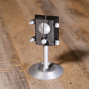 May include: A white ceramic mug with a black handle and the text "But First, Coffee" in a handwritten style. The mug is on a white surface. The mug is 10 cm tall.