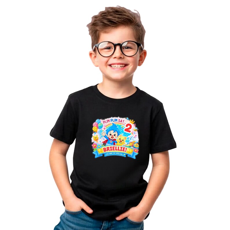 May include: A black short-sleeved t-shirt featuring a colorful graphic print on the chest. The design includes a cartoon character, a large red number 2, balloons, a rainbow, and the text Plim Plim Say, Briellie, and You Are So Special.
