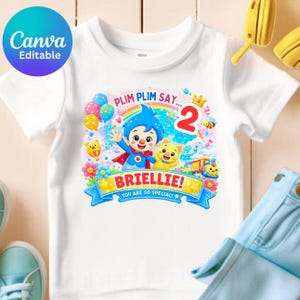 May include: A white short-sleeve t-shirt featuring a colorful graphic print of the character Plim Plim, a yellow cat, a rainbow, balloons, and a train. The text reads Plim Plim Say... 2, BRIELLIE!, and You Are So Special! in bright colors.