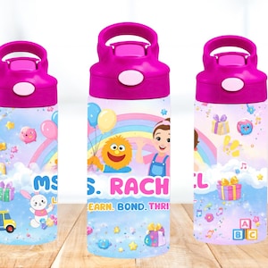 Puede incluir: Una taza de cerámica blanca con asa negra y el texto "But First, Coffee" en negrita negra. La taza se encuentra sobre un fondo borroso, sugiriendo un ambiente acogedor.