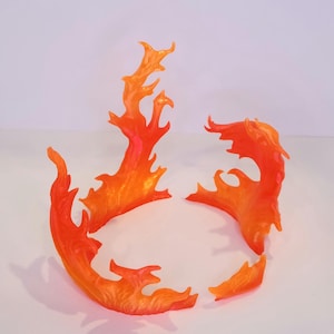 Puede incluir: Piezas de plástico con forma de llama naranja y amarilla. El conjunto incluye múltiples elementos de llama de varios tamaños, diseñados para simular fuego. Las piezas son translúcidas y están dispuestas sobre una superficie blanca.