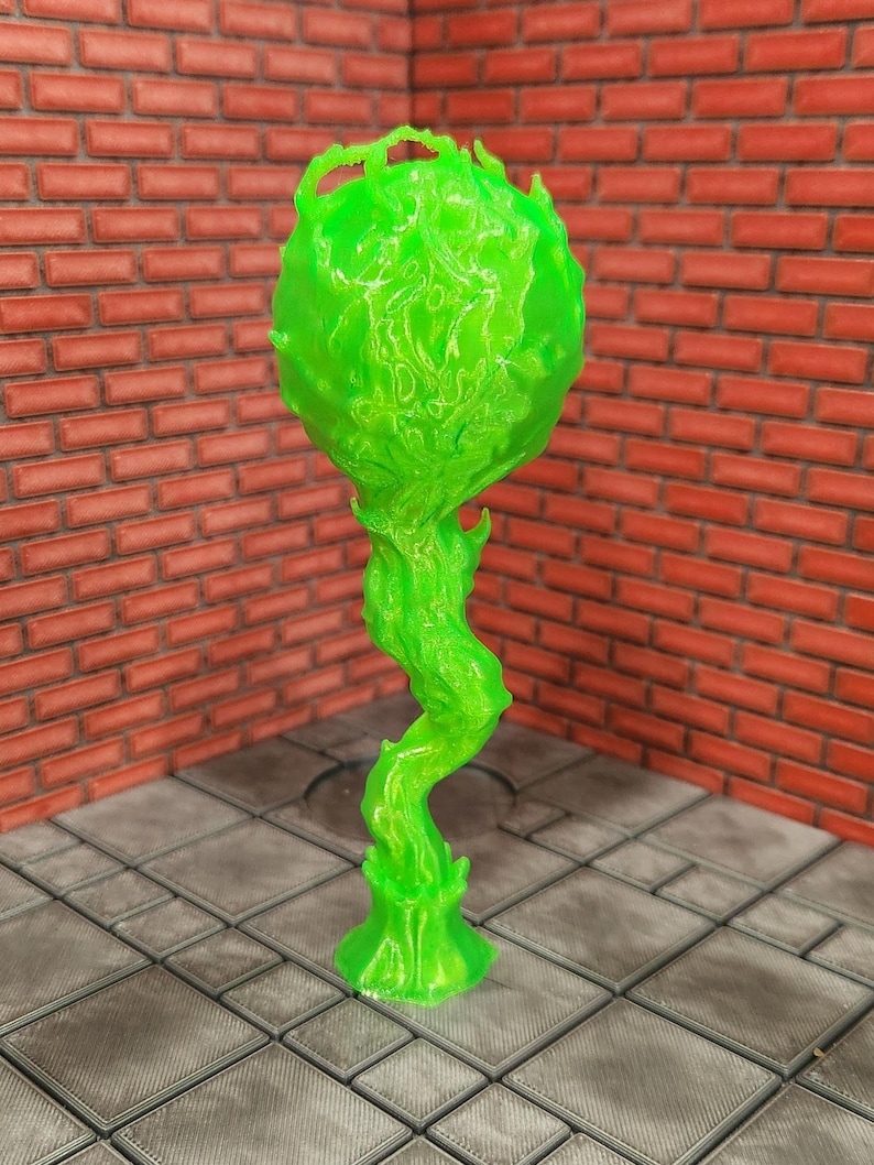 May include: A neon green, abstract sculpture with a bulbous top and a twisting, stem-like base. The sculpture has a textured surface and is set against a brick wall and tiled floor.