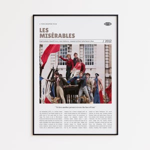 May include: A framed movie poster for "Les Misérables" (2012) featuring a cast photo of the actors. The poster has a black frame and includes the film's title, cast, and a quote. The image shows a scene with actors holding flags.