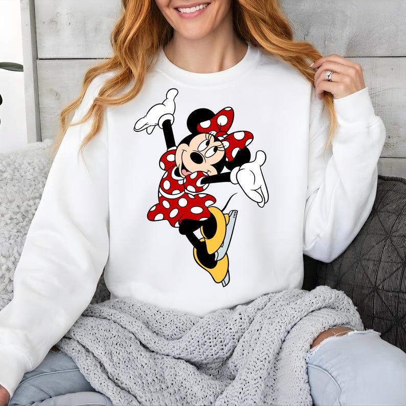 Puede incluir: Sudadera blanca con un dise&ntilde;o de dibujos animados de Minnie Mouse. Minnie aparece con un vestido rojo con lunares blancos, un lazo a juego y zapatos amarillos. El dise&ntilde;o est&aacute; centrado en la parte delantera de la parte superior de manga larga.