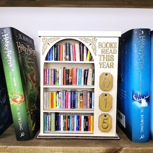 May include: A wooden bookshelf with the text "BOOKS READ THIS YEAR" and the numbers "015". The bookshelf is filled with miniature books. Two "Harry Potter" books flank the bookshelf.