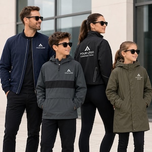 Può includere: Un gruppo di quattro persone che indossano vari capispalla, tra cui un bomber blu navy, una giacca a vento con cappuccio grigio antracite, una giacca nera con zip e un parka verde oliva, tutti con un logo a triangolo bianco e del testo.