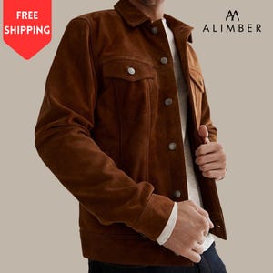 May include: A brown suede jacket with silver buttons and two chest pockets. The jacket has a classic collar and is worn over a white shirt. The brand name "ALIMBER" is visible in the upper right corner.