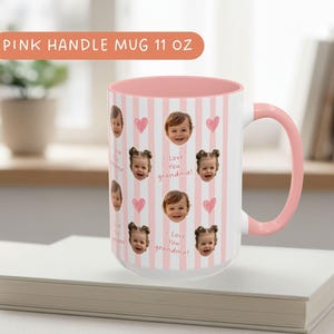 White ceramic mug with a pink and interior. The mug features a pattern of baby faces, pink hearts, and the text "I Love You Grandpa" on a rose striped background.