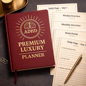 Peut inclure: Un agenda "ADHD Premium Luxury" de couleur bordeaux avec des lettres dorées et un motif de cerveau. L'agenda est ouvert sur plusieurs pages, dont "Daily Page - Day 1", "Weekly Overview" et "Monthly Overview". Un stylo doré repose sur les pages.