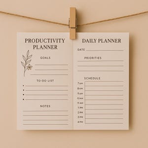 Peut inclure: Un agenda quotidien et un planificateur de productivité beiges, maintenus par une pince en bois. Le côté gauche indique "Productivity Planner" avec des sections pour les objectifs, la liste de tâches et les notes. Le côté droit indique "Daily Planner".