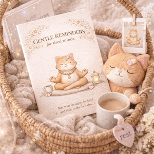 Peut inclure: Un panier en osier contient un journal avec le texte "GENTLE REMINDERS for tired minds" et un chat de dessin animé méditant. Un chat en peluche, une tasse à café et une petite étiquette avec "rest" sont également dans le panier.