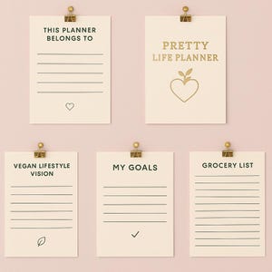 Peut inclure: Cinq feuilles de papier crème avec des pinces dorées. Les feuilles contiennent les textes : "This Planner Belongs To", "Pretty Life Planner", "Vegan Lifestyle Vision", "My Goals" et "Grocery List". Chaque feuille a un graphisme différent.