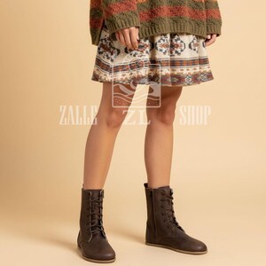 May include: Brown lace-up boots with a side zipper. The boots have a flat sole and are made of a matte material. The boots are worn with a patterned skirt and a sweater. The text "ZALLE ZI SHOP" is visible on the image.