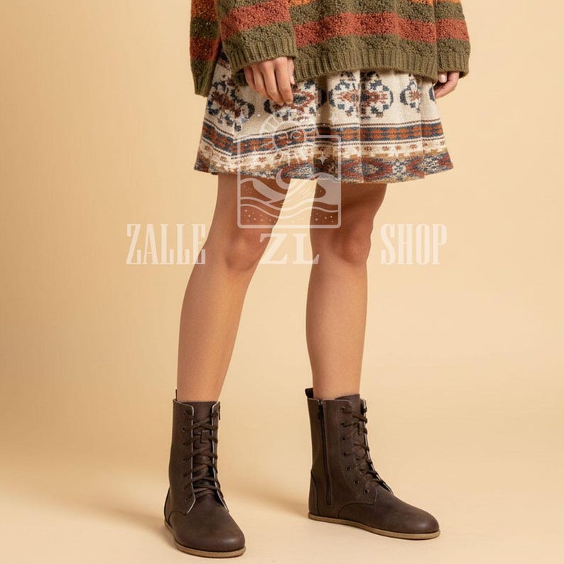 May include: Brown lace-up boots with a side zipper. The boots have a flat sole and are made of a matte material. The boots are worn with a patterned skirt and a sweater. The text "ZALLE ZI SHOP" is visible on the image.
