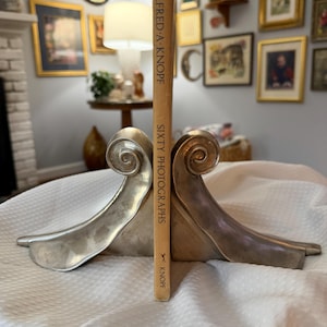 Sujetalibros antiguos de plata con volutas, detalle decorativo para el hogar al estilo Hollywood Regency.