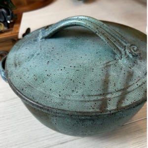 Könnte beinhalten: Rustikales Holzschild mit dem Text "Welcome to our home" in weißer Schrift. Das Schild hat eine Used-Optik und ein schlichtes, einladendes Design, ideal für die Dekoration der Haustür.