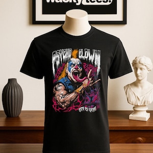 May include: Black t-shirt featuring a colorful graphic of a menacing clown with the words "PSYCHO CLOWN" above the image. The text "ESTO ES LUCHA!" is below the image. The brand "wacky tees." is displayed in a black frame.