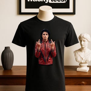 May include: Black t-shirt featuring an image of a person wearing a red leather jacket. The image is a graphic design. The text "wacky tees." is in a black frame in the background.