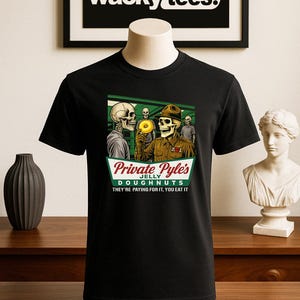 May include: Black t-shirt featuring a graphic of skeleton soldiers with a donut and the text "Private Pyle's Jelly Doughnuts. They're paying for it, you eat it." The shirt has the "wacky tees." logo.