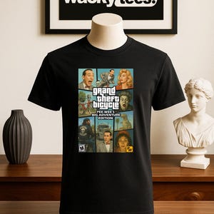 May include: Black t-shirt with a graphic design featuring the text "Grand Theft Bicycle: Pee Wee's Big Adventure Edition." The design incorporates images of characters from the film. The t-shirt is displayed on a mannequin.
