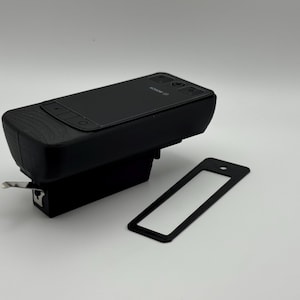 Op de afbeelding: Een zwart elektronisch apparaat met een rechthoekige vorm, met een scherm en knoppen, en een apart zwart frame. Het apparaat heeft de merknaam "BOSCH" erop gedrukt. De items staan op een witte achtergrond.