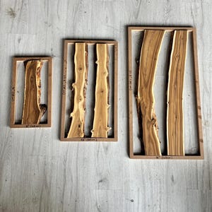 May include: Three wooden wall art pieces. Each piece features a natural wood slab set within a rectangular frame. The sizes are 8" (20cm), 12" (30cm), and 16" (40cm) wide. The wood has a light brown color.