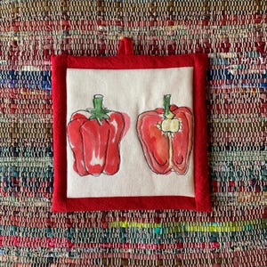 May include: A square, red-trimmed potholder with a white center featuring a watercolor illustration of two red bell peppers. One pepper is whole, and the other is cut in half, showcasing the interior.
