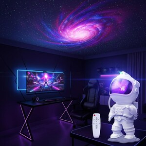 May include: A white astronaut-shaped galaxy projector sits on a black table, with a remote control beside it. The projector displays a swirling galaxy on the ceiling, with a gaming setup in the background. The room is illuminated with purple and blue lighting.