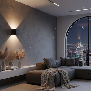 Puede incluir: Salón moderno con un sofá seccional gris oscuro, una gran ventana arqueada con vistas a un horizonte urbano nocturno y una lámpara de pared negra. Jarrones decorativos y plantas sobre una estantería blanca.