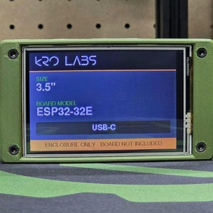 May include: An olive green rectangular enclosure for a 3.5 inch display screen. The screen displays the text KRO LABS, SIZE 3.5", BOARD MODEL ESP32-32E, USB-C, and ENCLOSURE ONLY - BOARD NOT INCLUDED. The frame is secured with four black screws.