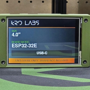 Puede incluir: Una carcasa electrónica rectangular de color verde oliva con una pantalla de 10,16 cm que muestra el texto KRO LABS, SIZE 4.0, BOARD MODEL ESP32-32E, USB-C y ENCLOSURE ONLY - BOARD NOT INCLUDED. El dispositivo tiene cuatro tornillos negros.