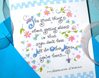 May include: A white card with blue and white checkered border and a handwritten quote in blue ink. The quote reads "The great thing about getting older is that you don't lose all the other ages you've been..." and is signed "~Madeleine L'Engle".