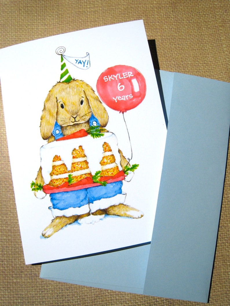 May include: A birthday card featuring a cartoon bunny wearing a cake for a shirt and holding a red balloon that says "Skyler 6 years". The bunny is wearing a party hat that says "Yay!"