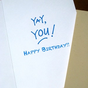 May include: A white card with blue ink that says "Yay, You! Happy Birthday!"