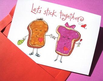 May include: A white card with a red envelope. The card has a hand-drawn illustration of two pieces of bread with faces. One piece of bread has peanut butter and the other has jelly. The text on the card says "Let's stick together".