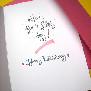 May include: A white card with a pink envelope. The card has blue and pink lettering that says "Have a fun 'n frisky day!" and "Happy Birthday".