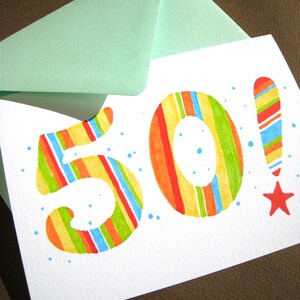 May include: A white card with a colorful striped number "50" and a red star. The card is decorated with blue dots and has a light green envelope on top.