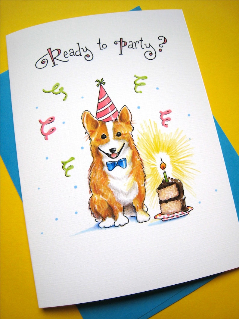 May include: A birthday card featuring a cartoon illustration of a corgi wearing a party hat and a bow tie, with a single candle on a cake in the background. The card reads "Ready to Party?"